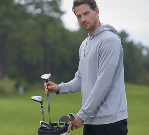 Model wearing MAELREG Classic Heather Golf Hoodie takes a club from bag, calm and focused.