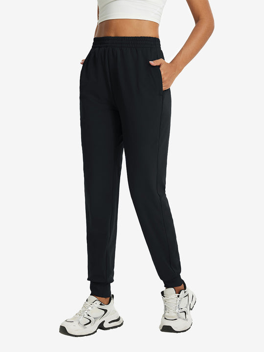 Model with hand in pocket wearing lightweight women's stretchy joggers sweatpants in black.