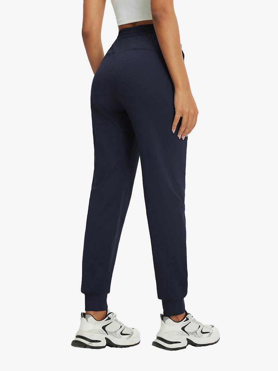 Back view of lightweight women's stretchy joggers sweatpants on model, shown in navy.