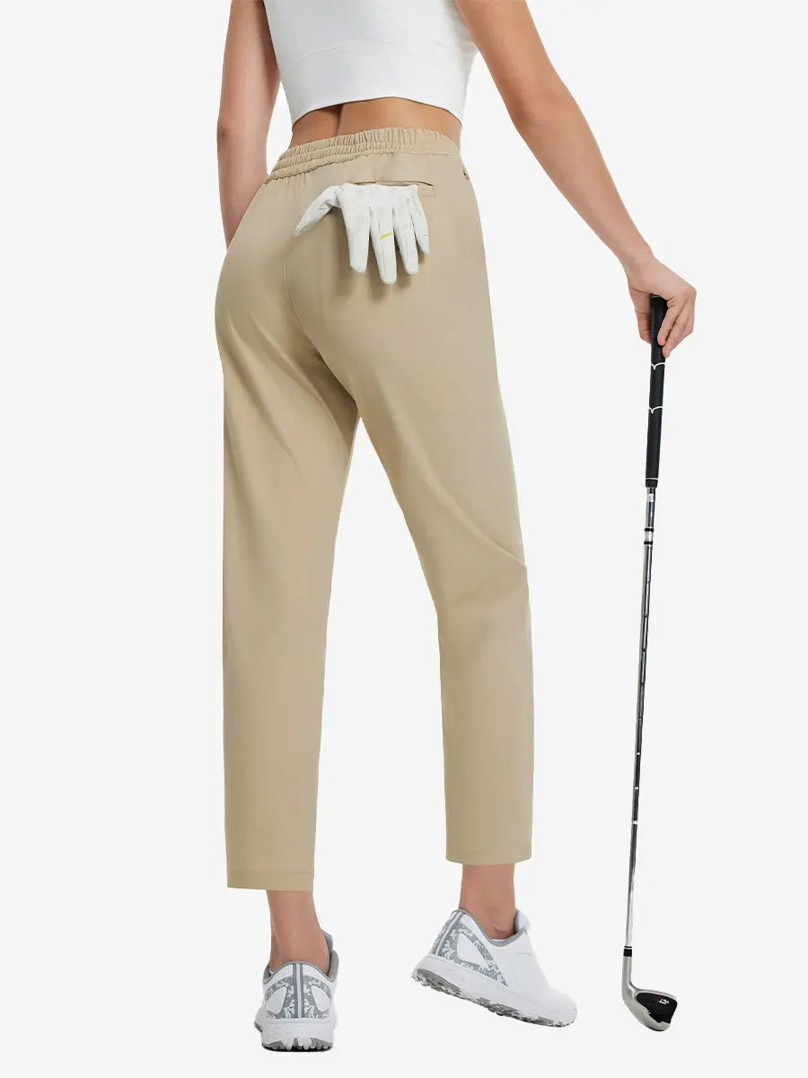 Back lower-body view holding a golf ball with glove in rear pocket wearing Khaki Women's 7/8 Ankle Golf Track Pants.