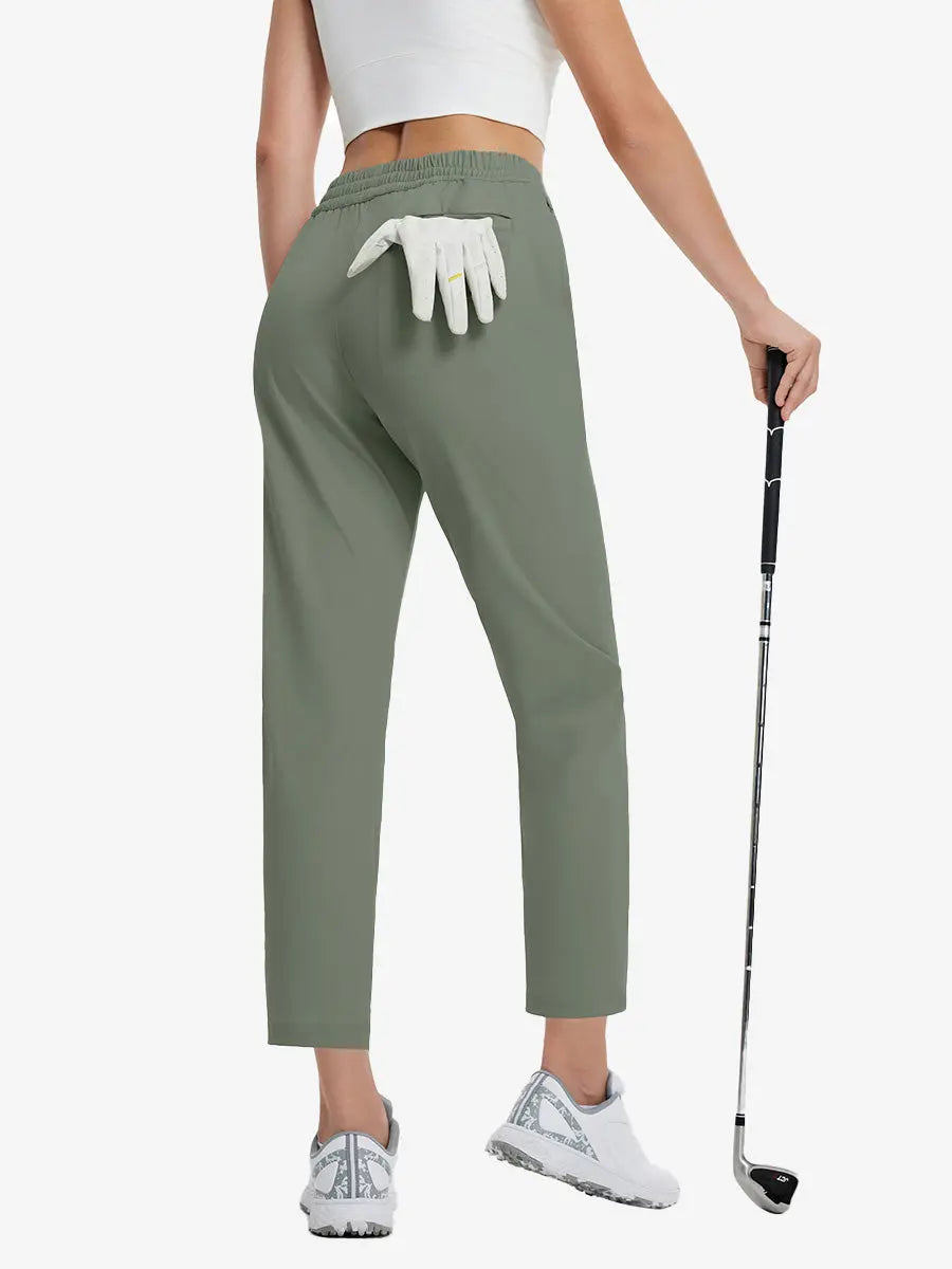 Back lower-body view holding a golf ball with glove in rear pocket wearing OLIVE GREEN Women's 7/8 Ankle Golf Track Pants.