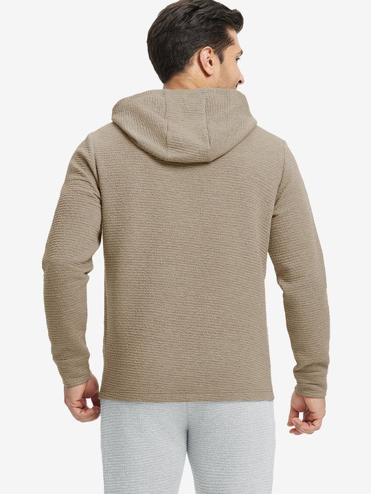 Back view of model wearing texture solid hoodies pullover showing fit and hood detail, light brown heather.