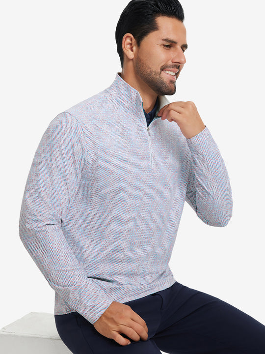 Model seated on chair, wearing full print quarter zip pullover in colorful hexagon, casual upper body view.