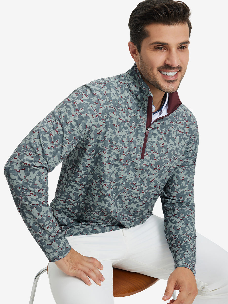 Model seated on chair, wearing full print quarter zip pullover in grey/wine camo, casual upper body view.