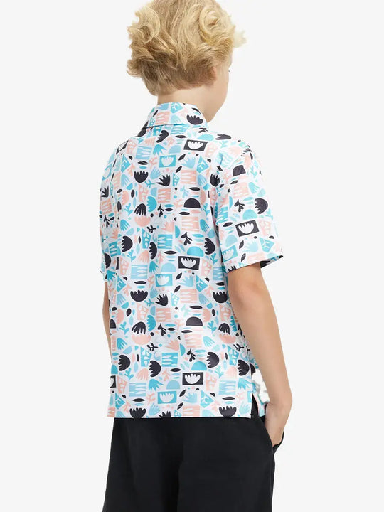 Back half-body view of boy wearing IRREGULAR GEO Performance Print Boys Golf Polo outdoors