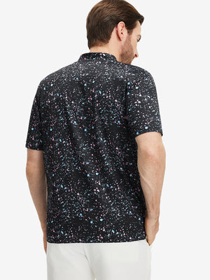 Back half-body of model in black splatter stretch printed collarless henley golf shirts