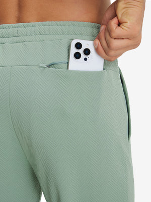 Close-up of iPhone partly inside pocket of beryl green soft sweatpants with 4 zipper pockets