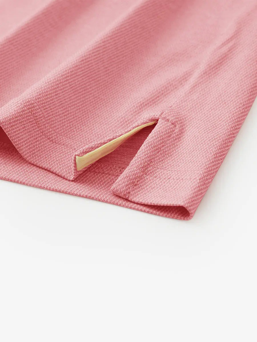 Hem slit detail of PINK HEATHER Premium Stretch Heather Polo highlighting stitching and finish.