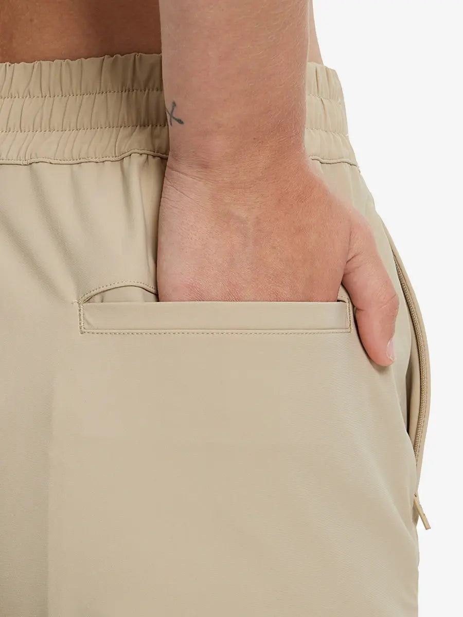 Back view with hand in rear pocket wearing Khaki Women's 7/8 Ankle Golf Track Pants.