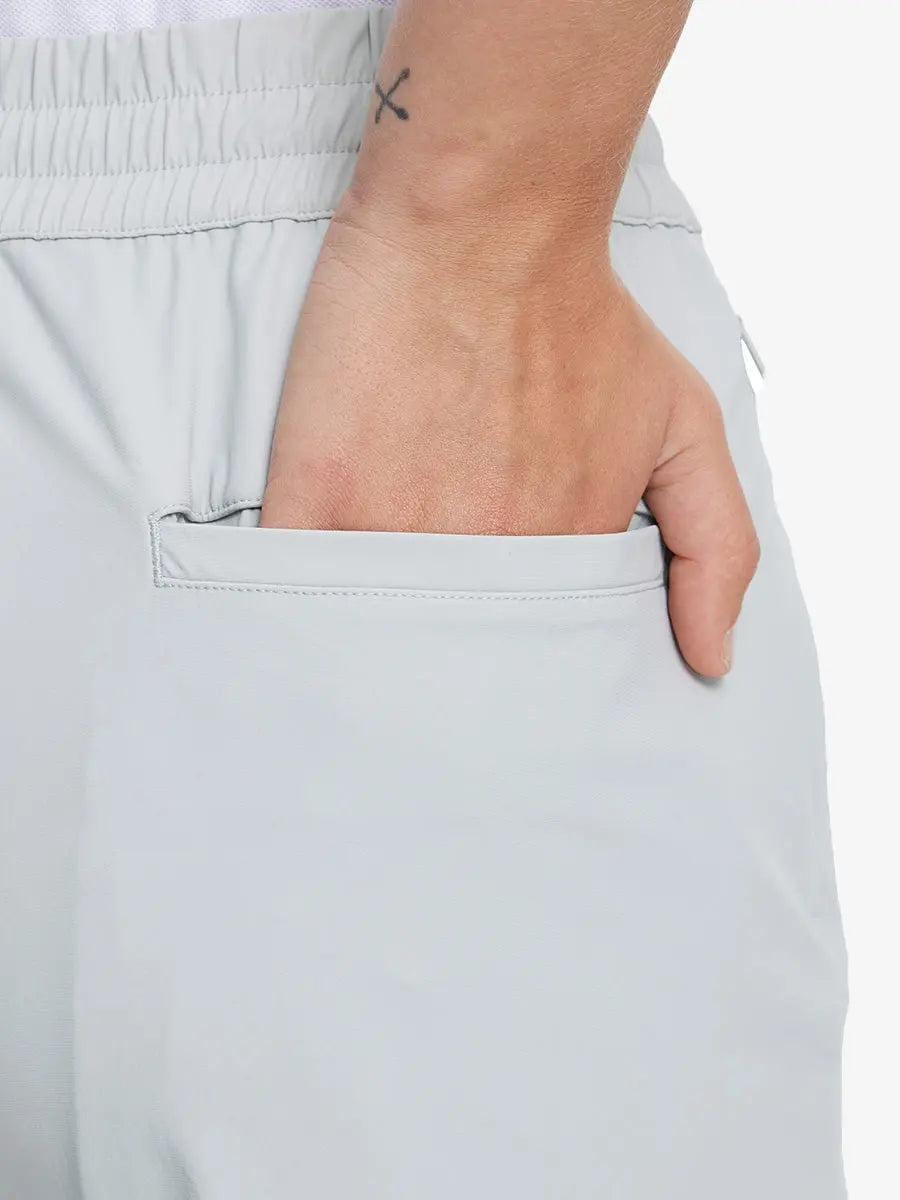 Back view with hand in rear pocket wearing GLACIER GREY Women's 7/8 Ankle Golf Track Pants.