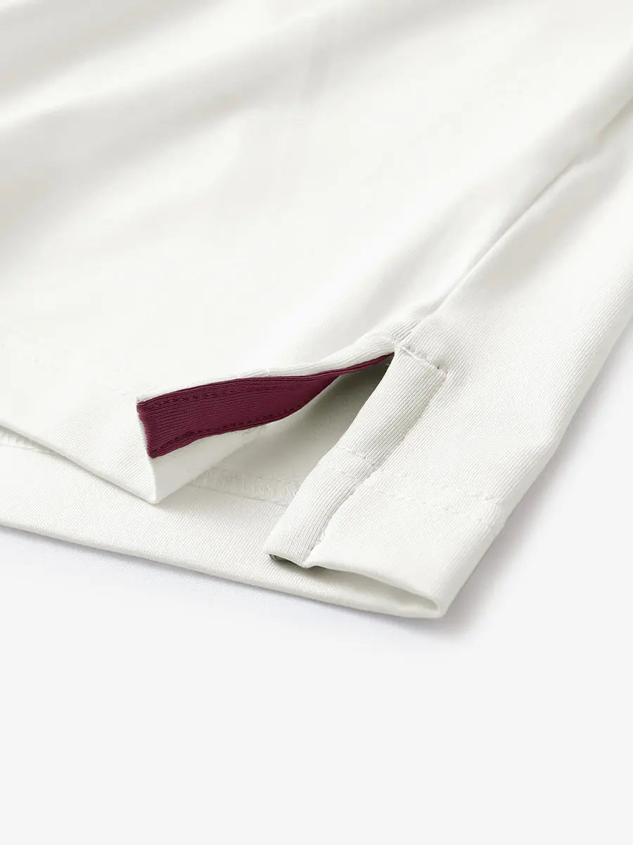 Hem slit detail of CREAM Moisture Wicking Color Block Polo Shirt highlighting stitching and finish.