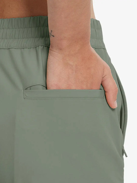 Back view with hand in rear pocket wearing OLIVE GREEN Women's 7/8 Ankle Golf Track Pants.