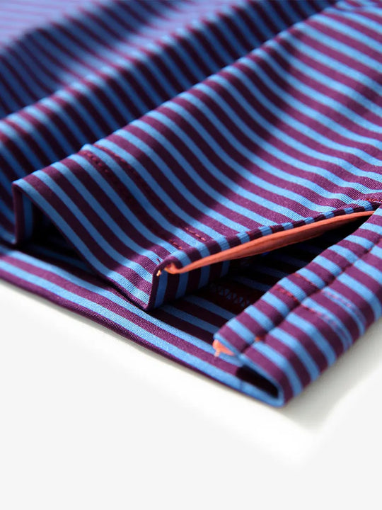 Close-up of side hem slit on PLUM BLUE STRIPE polo, detailing for comfort and mobility