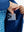 Model holding a golf club, wearing boys windproof puffer jacket with pockets in klein blue, full-body.