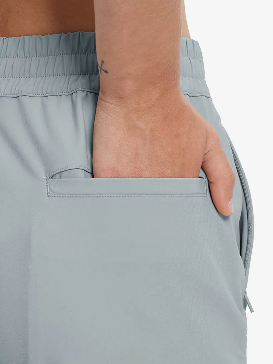 Back view with hand in rear pocket wearing LIGHT GREY Women's 7/8 Ankle Golf Track Pants.