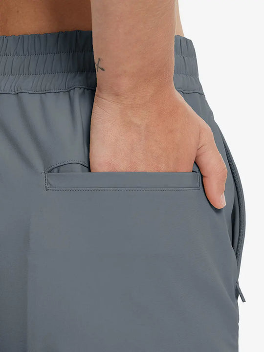 Back view with hand in rear pocket wearing DARK GREY Women's 7/8 Ankle Golf Track Pants.