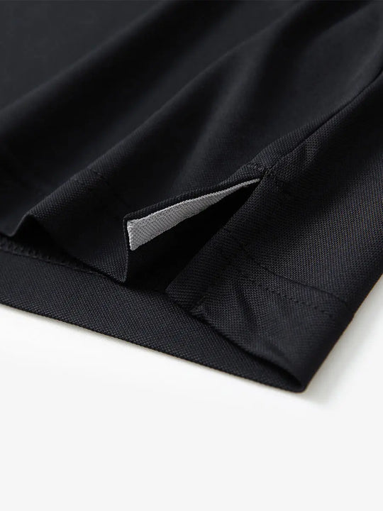 Detail view of the black long sleeve pique polo, showcasing the hem opening and refined design.