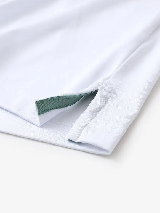 Hem slit detail of WHITE Moisture Wicking Color Block Polo Shirt highlighting stitching and finish.