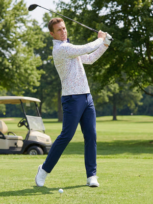 Model swinging on golf course wearing full print lightweight quarter zip pullover in white polka dots