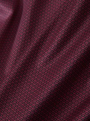 Macro view of the burgundy geometric 4 way stretch print collared polo shirt fabric, showcasing the unique print design