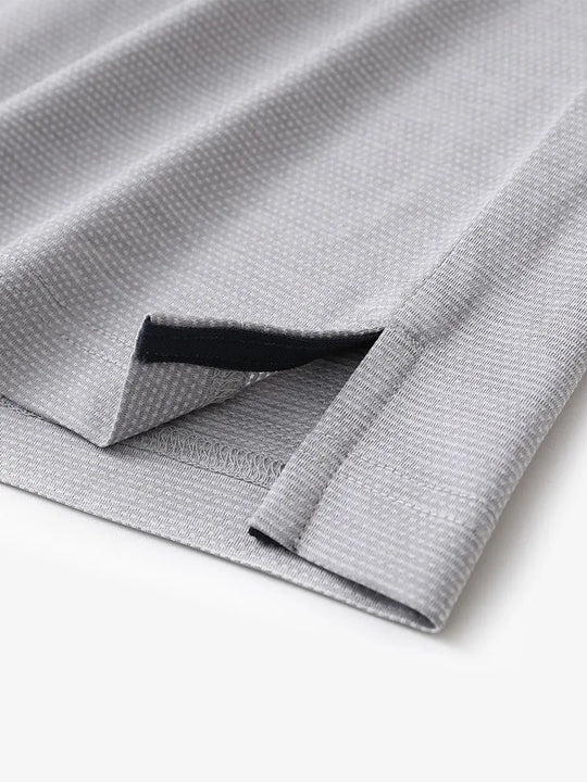 Close-up of side hem slit on Ventilated Heather Jacquard Polo in FADED DENIM HEATHER, showing detail