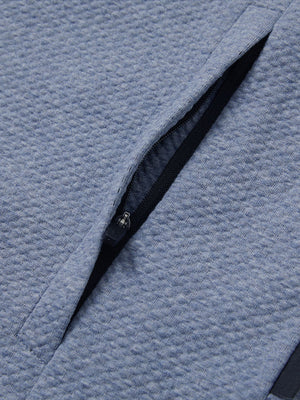 Close-up of jacket pocket showing fine stitching and insulation detail, textured insulated winter jacket, blue heather.