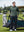 Model in green heather classic heather fleece hoodies standing in front of a golf cart on the course